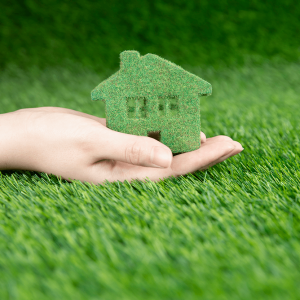 man-holds-his-hand-small-eco-house-background-grass